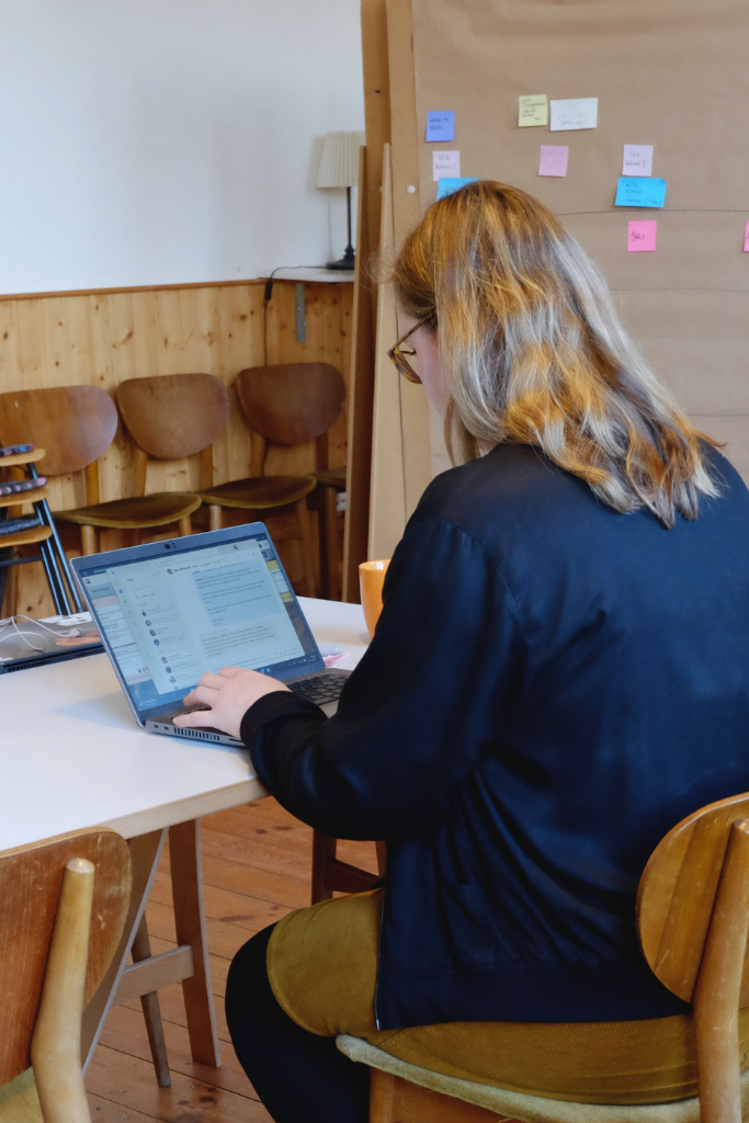 Bianca Beraterin bei Guter Move sitzt am Laptop an einem langen Tisch und tippt